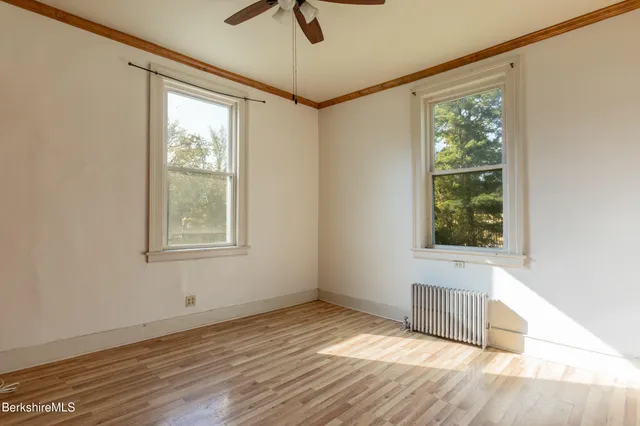 a view of an empty room with a window and wooden floor