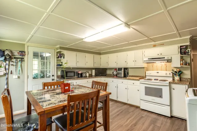 a open kitchen with stainless steel appliances granite countertop a stove and white cabinets