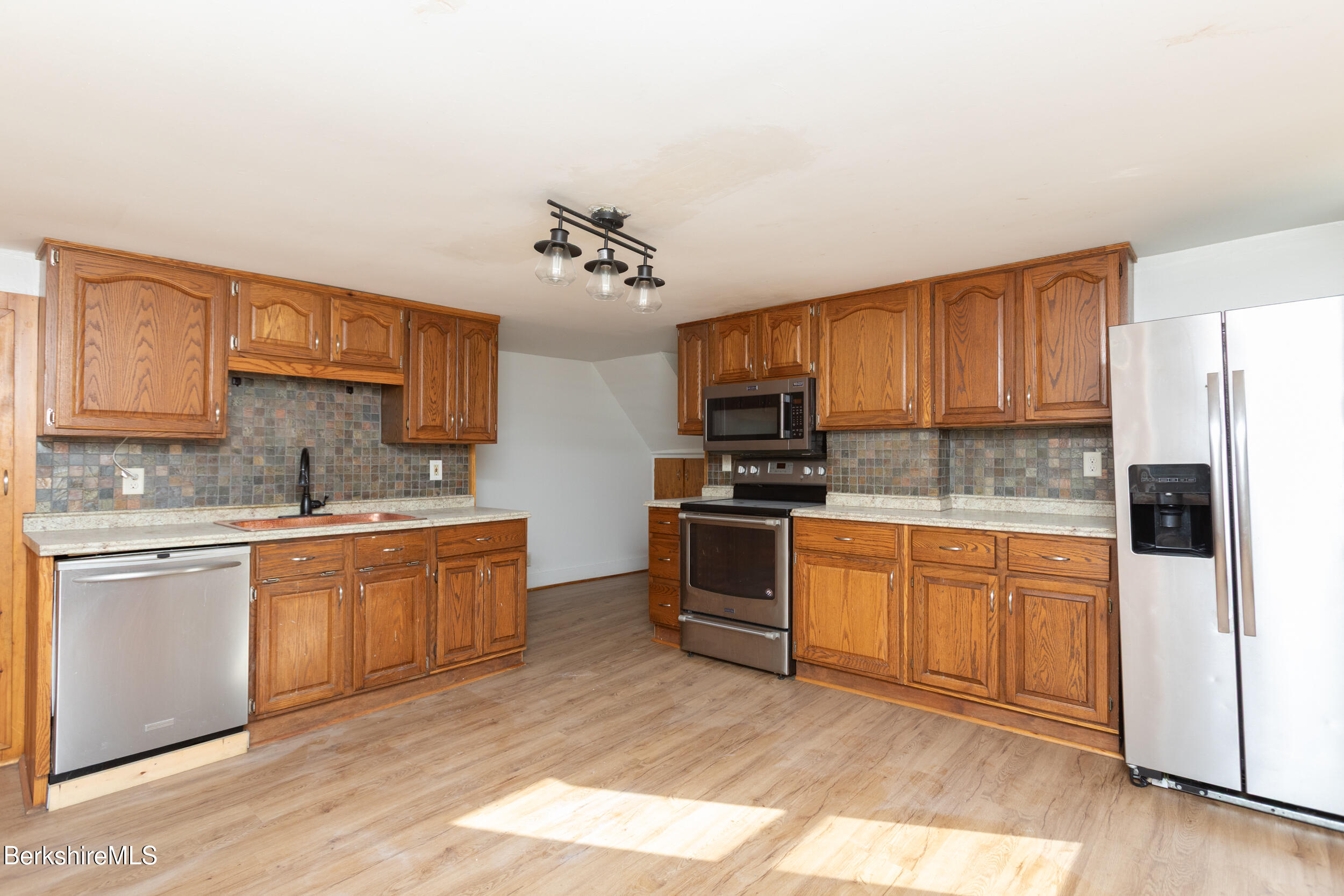 89-91 Pecks Road Pittsfield, MA 01201 - Photo 4 of 28 a kitchen with stainless steel appliances granite countertop a stove top oven a sink and dishwasher a refrigerator with wooden floor