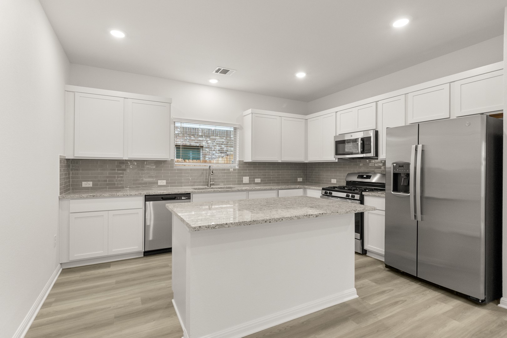 18605 Emu Lane Manor, TX 78653 - Photo 11 of 27 The kitchen features white cabinetry, stainless steel appliances, and a central island with a granite countertop