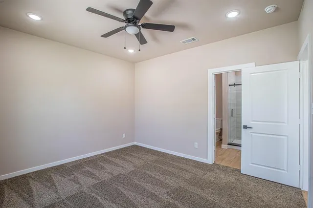 an empty room with a ceiling fan and a carpet