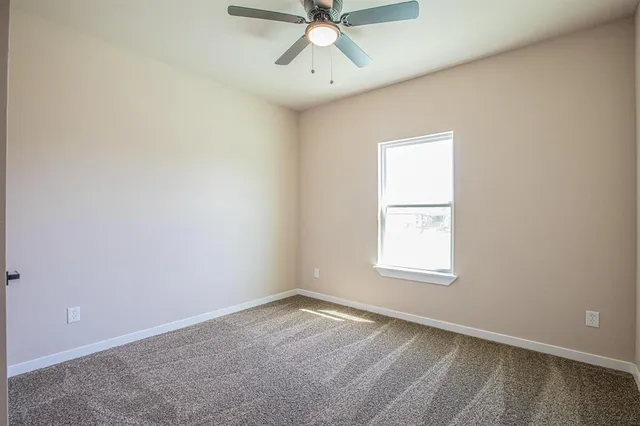 an empty room with a window and a fan
