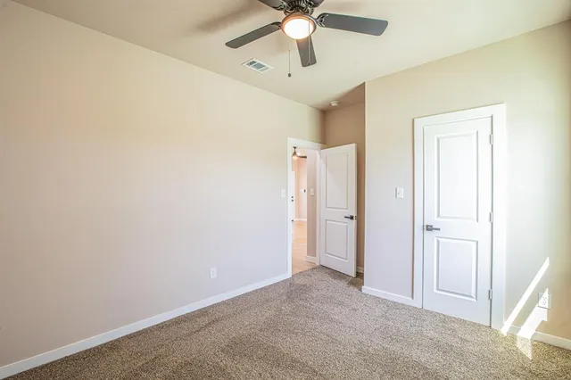 an empty room with closet and a chandelier fan