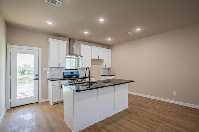 a kitchen with stainless steel appliances granite countertop a sink stove and wooden floor