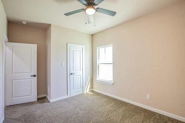 an empty room with windows and fan