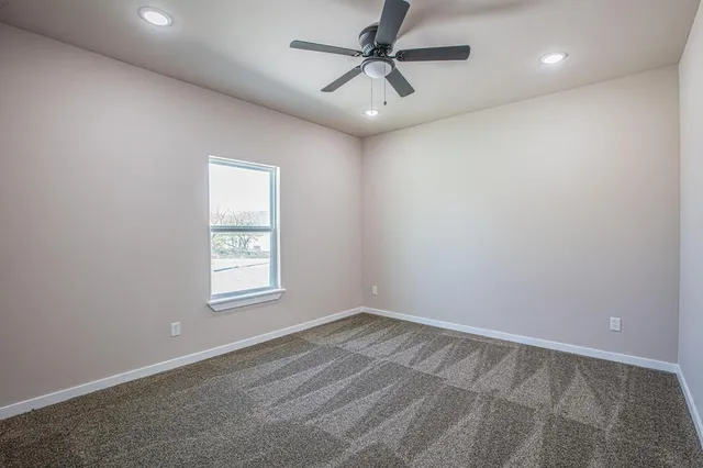 an empty room with a window and a fan