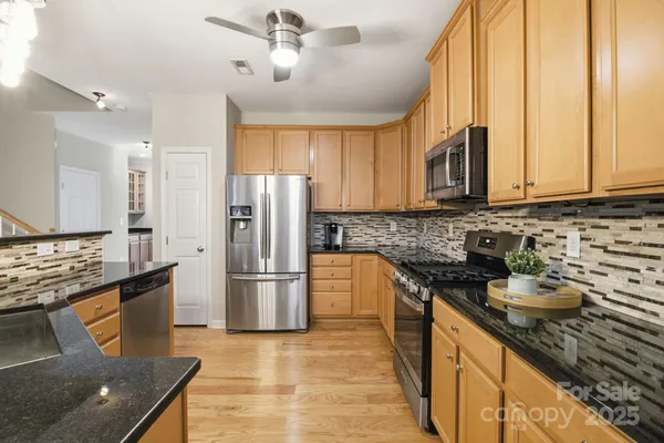a kitchen with stainless steel appliances granite countertop a refrigerator a stove and a sink