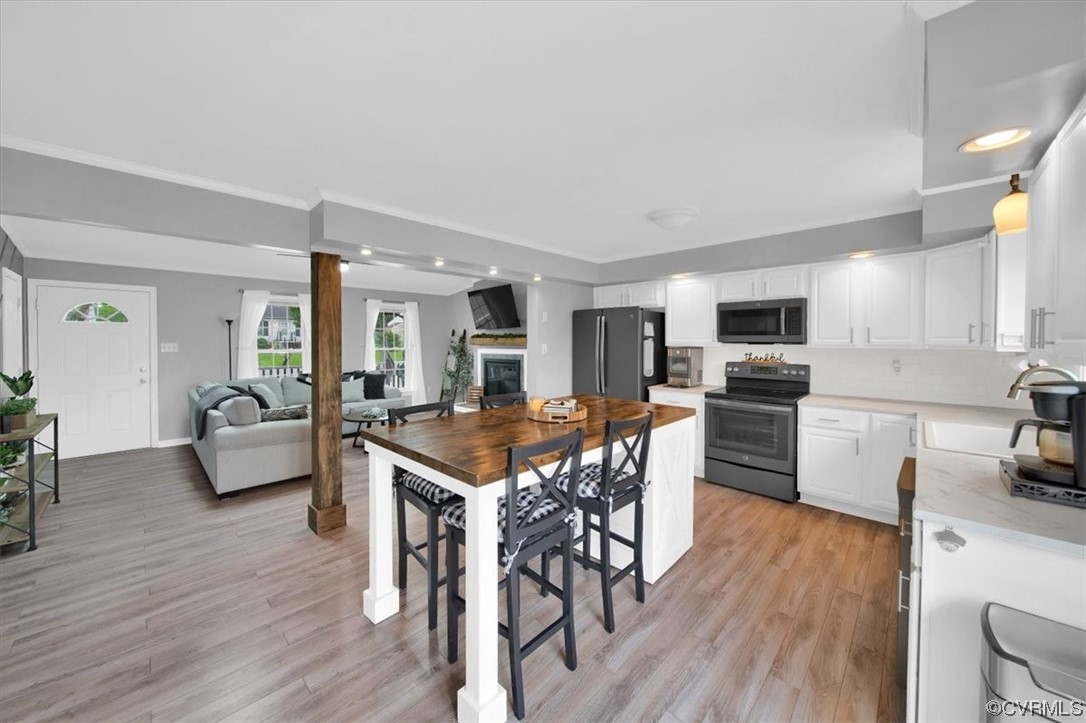 7719 Drexelbrook Road Chesterfield, VA 23832 - Photo 16 of 49 a kitchen with stainless steel appliances a dining table chairs stove microwave and wooden floor