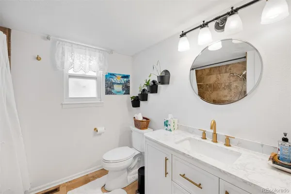 a bathroom with a granite countertop sink mirror vanity and toilet