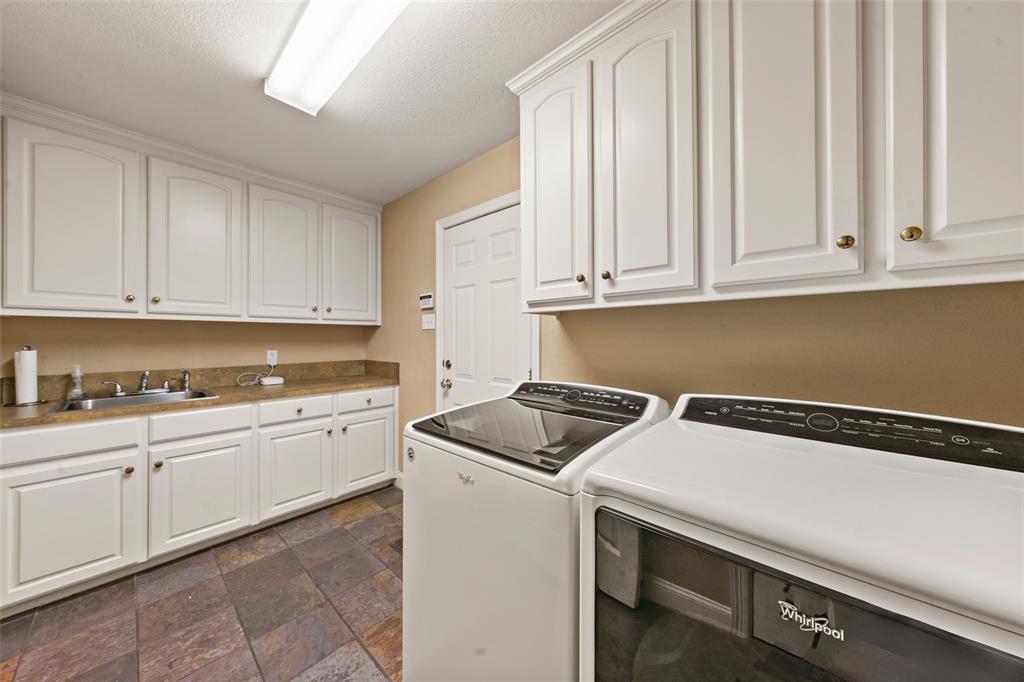517 Chado Lane Robinson, TX 76706 - Photo 15 of 40 Laundry area featuring dark stone finish flooring, washer and clothes dryer, and cabinet space