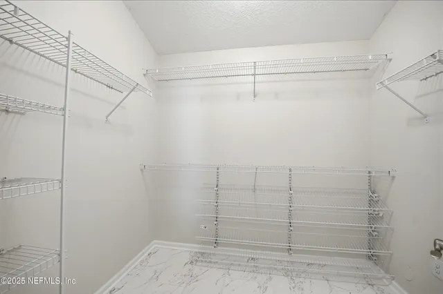 an empty room with chandelier fan and windows