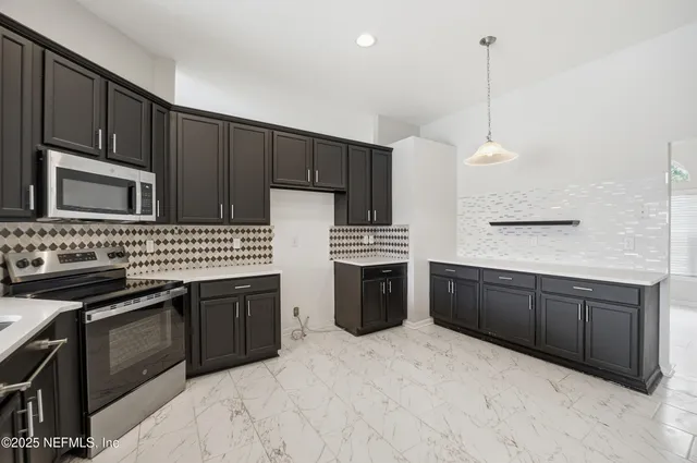 a kitchen with stainless steel appliances granite countertop a stove a sink and a microwave