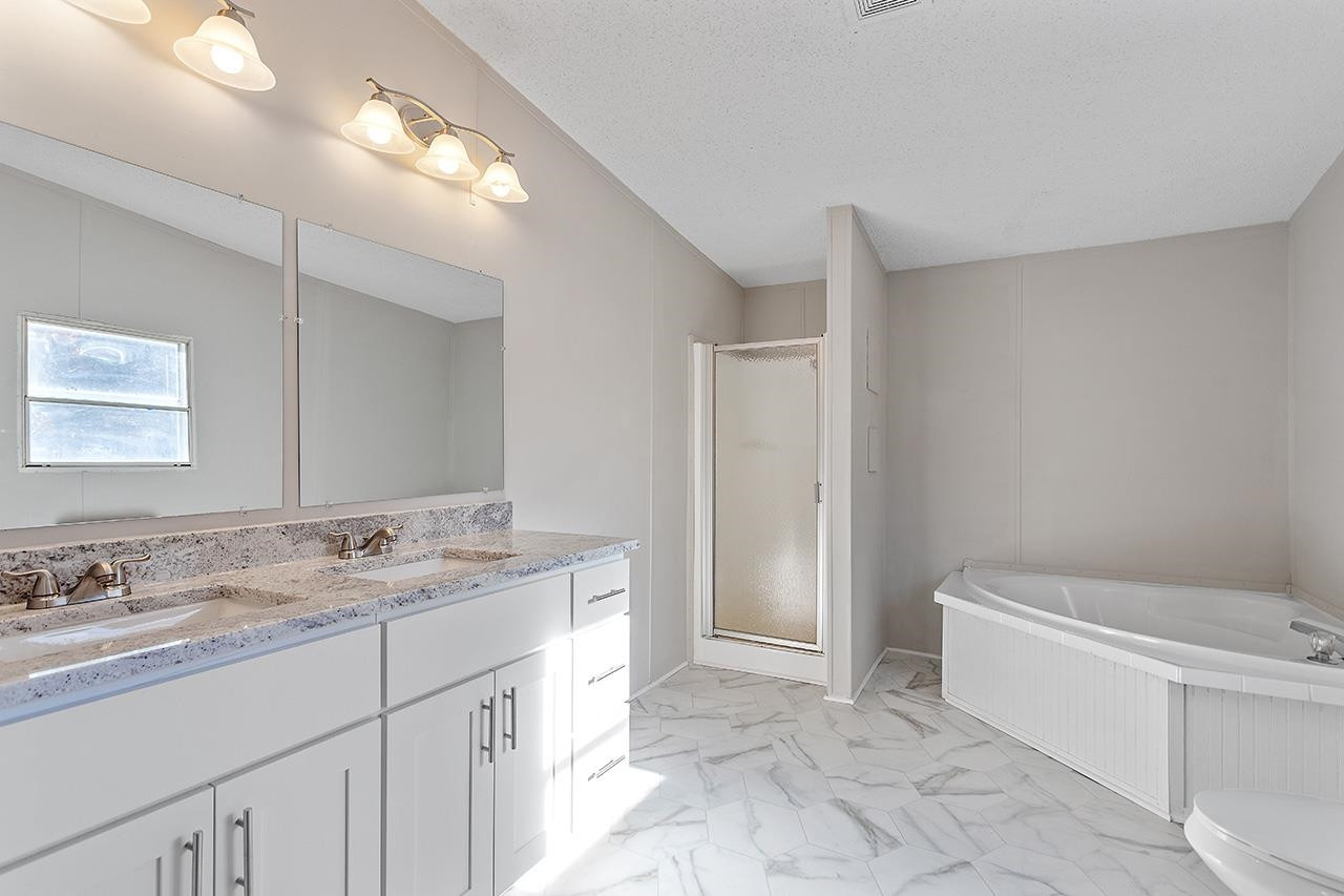 8401 South Creek Road Willow Spring, NC 27592 - Photo 8 of 24 a spacious bathroom with a granite countertop sink a toilet mirror and a bathtub