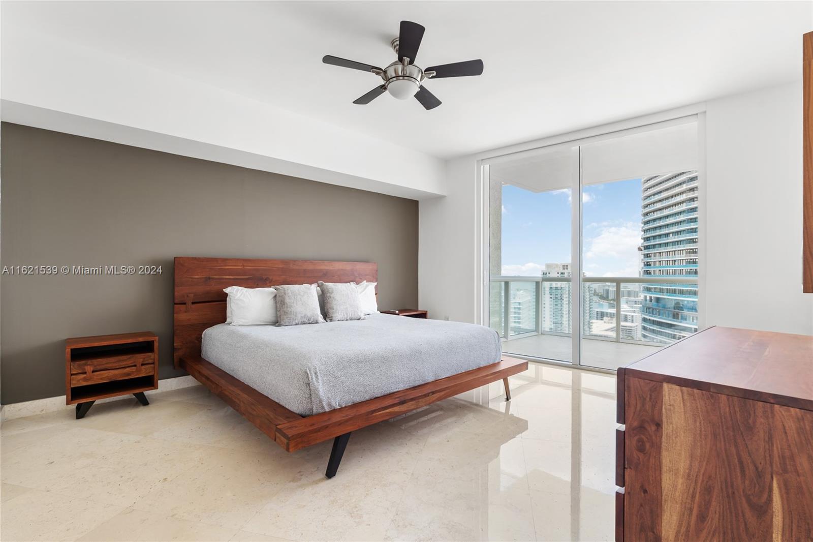450 Alton Road, Unit 3106 Miami Beach, FL 33139 - Photo 22 of 40 a bedroom with a bed a chandelier and a flat tv