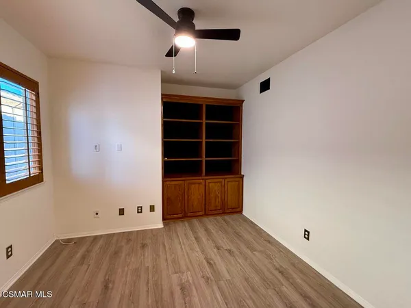 an empty room with wooden floor cabinet and windows