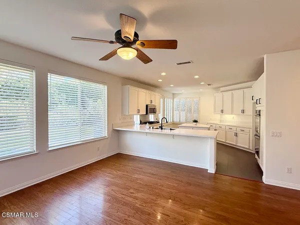 a view of a kitchen with wooden floor a sink a refrigerator and window