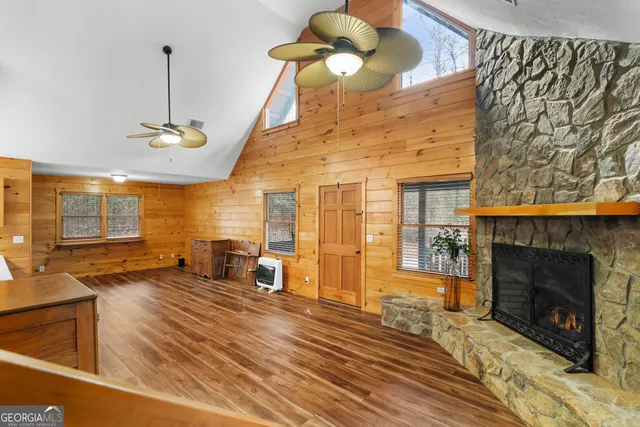 a view of an empty room with wooden floor fireplace and a window