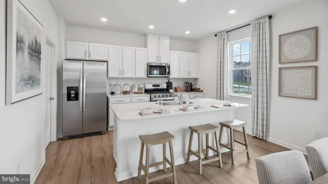 a kitchen with stainless steel appliances granite countertop a refrigerator a sink a stove a dining table and chairs