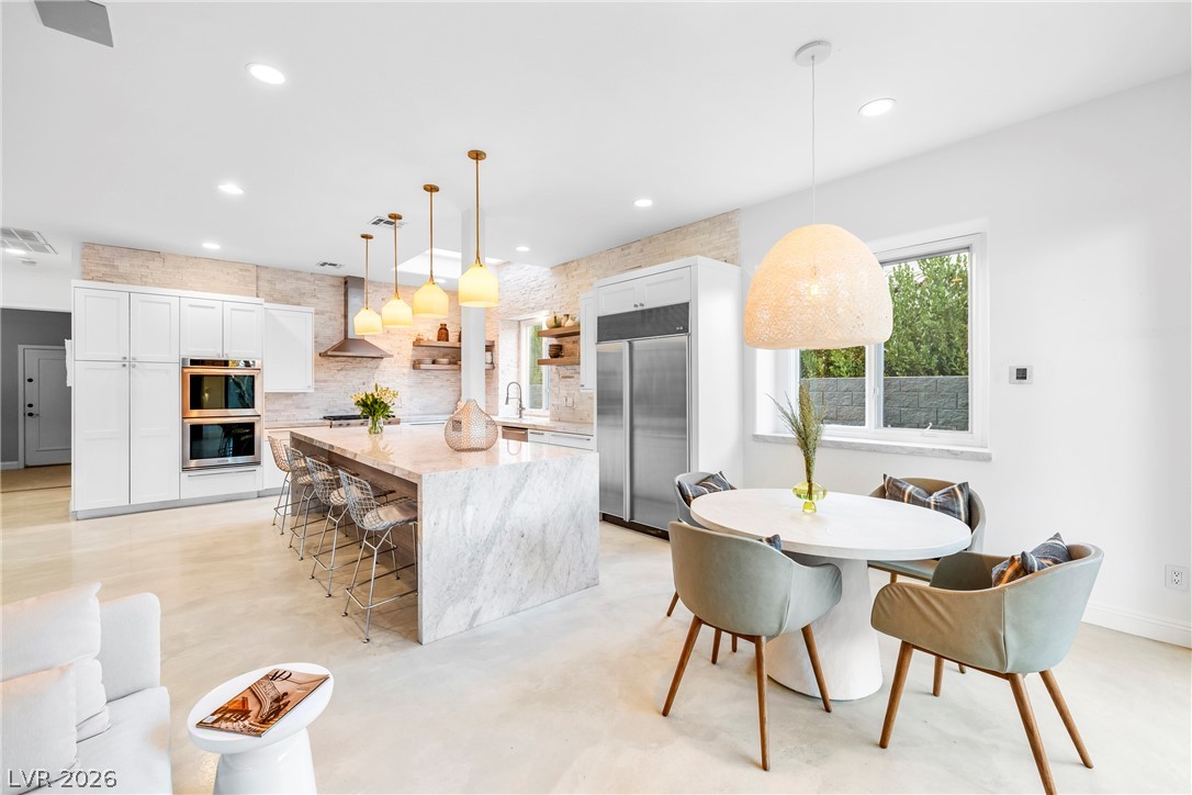 2000 Grouse Street Las Vegas, NV 89134 - Photo 21 of 89 A luminous kitchen and dining area features sleek appliances, a substantial island, and warm pendant lighting.