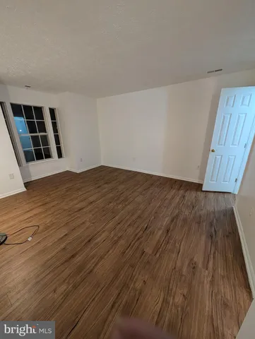 a view of an empty room with wooden floor and staircase