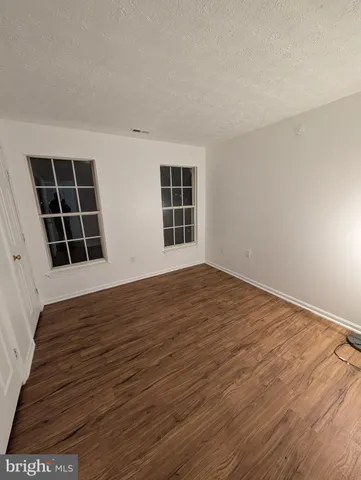 a view of empty room with wooden floor and windows