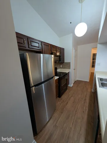 a kitchen with stainless steel appliances a refrigerator sink and wooden floor