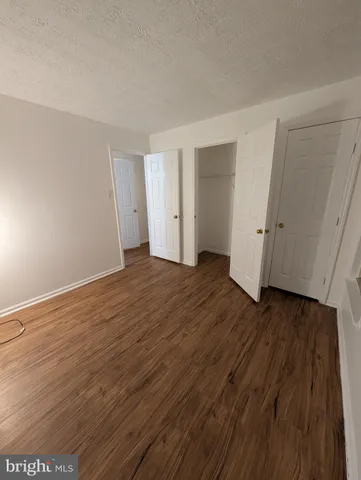 a view of an empty room with wooden floor and closet
