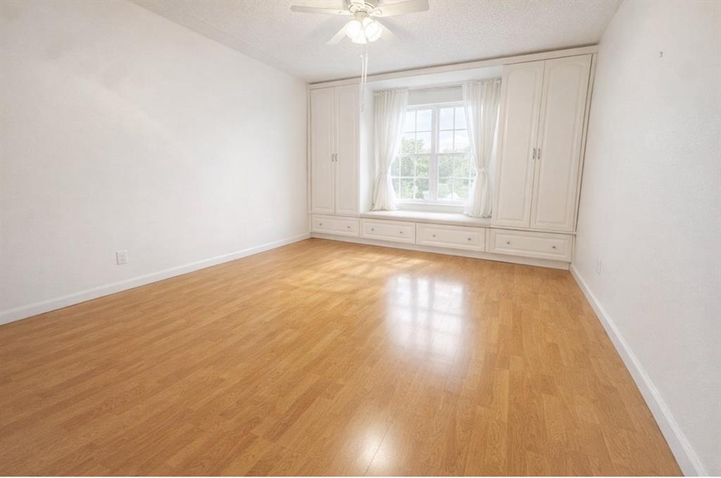 6750 Northeast 21st Road, Unit 123 Fort Lauderdale, FL 33308 - Photo 6 of 12 an empty room with wooden floor chandelier fan and windows