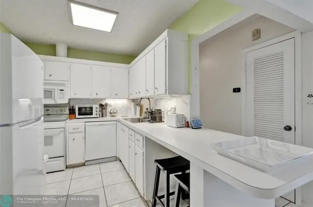 a kitchen with a sink white cabinets and white appliances