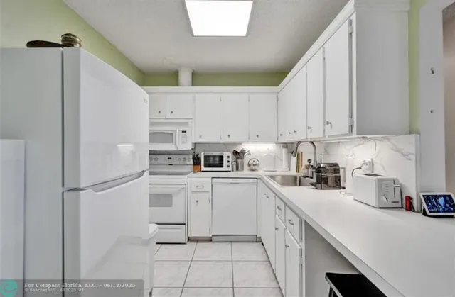 a kitchen with white cabinets and white appliances