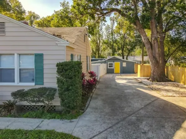 a view of a white house next to a road and trees