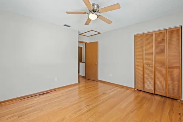 an empty room with wooden floor chandelier fan and closet