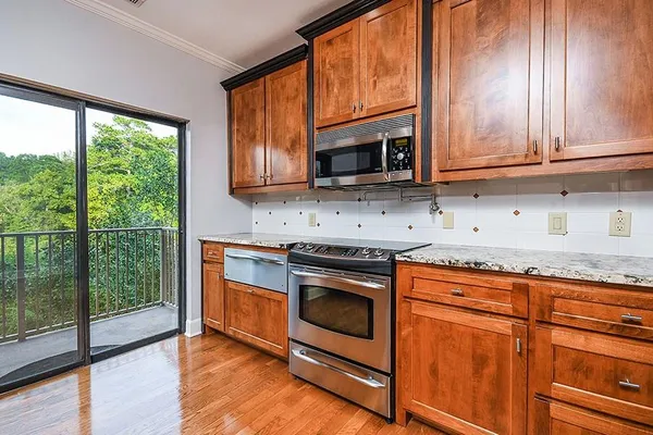 a kitchen with granite countertop wooden cabinets stainless steel appliances and a large window