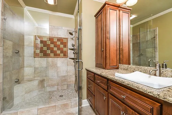 a bathroom with a granite countertop sink a mirror and shower