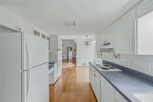 a kitchen with stainless steel appliances a refrigerator a sink and white cabinets