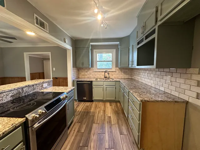 a large kitchen with stainless steel appliances granite countertop a stove and a sink