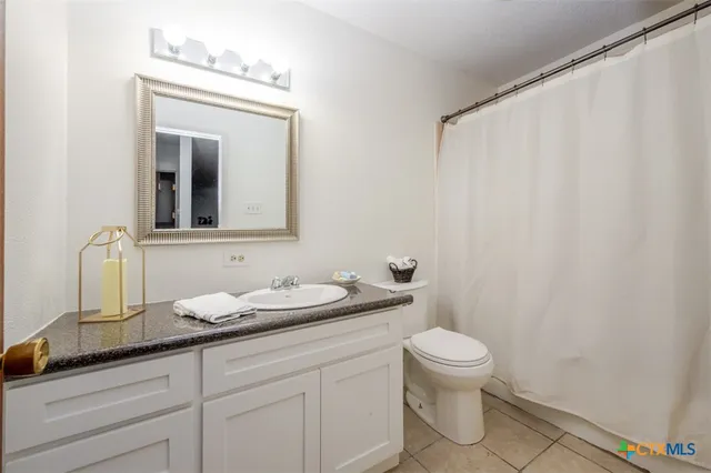 a bathroom with a granite countertop sink a toilet and a mirror