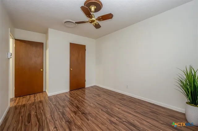 a view of room with hardwood floor and a ceiling fan