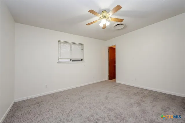an empty room with a chandelier fan and wooden floor
