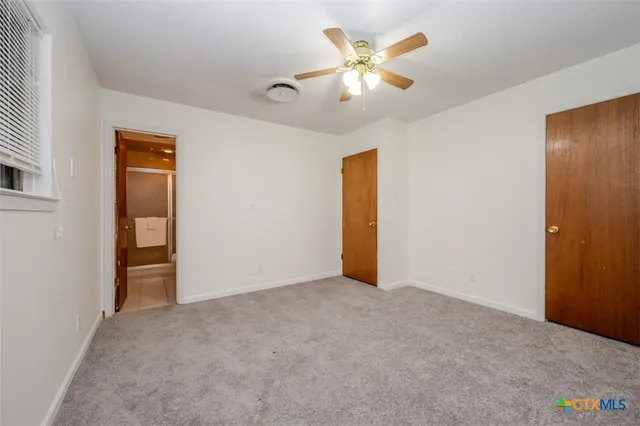 an empty room with closet and a chandelier fan