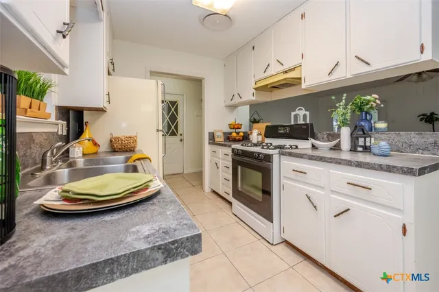 a kitchen with stainless steel appliances granite countertop a sink a stove and a wooden cabinets