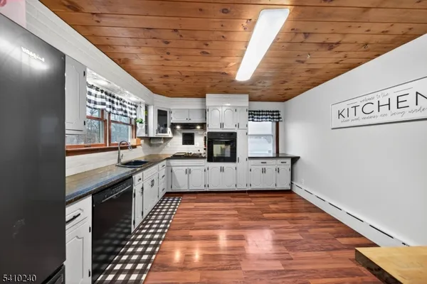 a kitchen with stainless steel appliances granite countertop a refrigerator a sink dishwasher a stove and white countertops with wooden floor