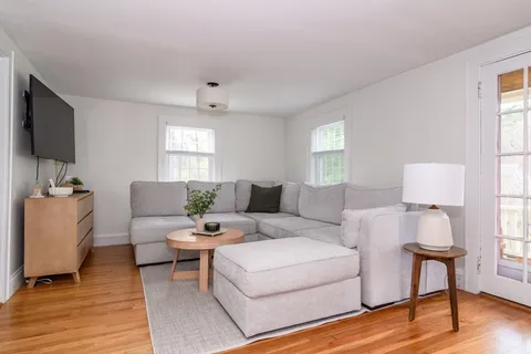 a living room with furniture a flat screen tv and a window
