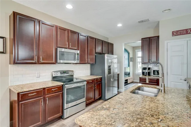 a kitchen with stainless steel appliances granite countertop a stove refrigerator sink and cabinets