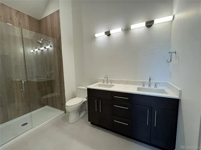 a bathroom with a double vanity sink toilet and shower