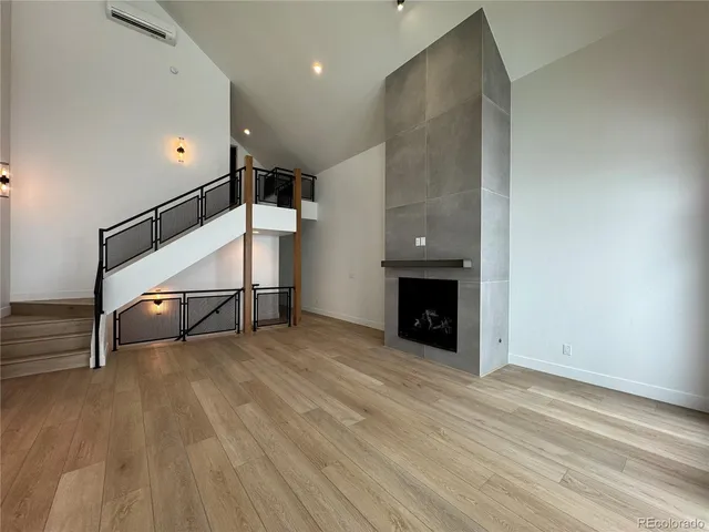 a view of an empty room with wooden floor a fireplace