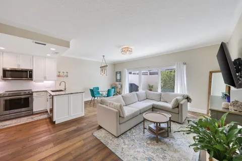 a living room with furniture a flat screen tv and kitchen view