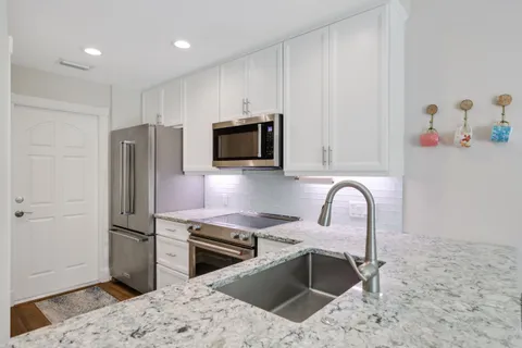 a kitchen with stainless steel appliances granite countertop a stove top oven a sink and a refrigerator