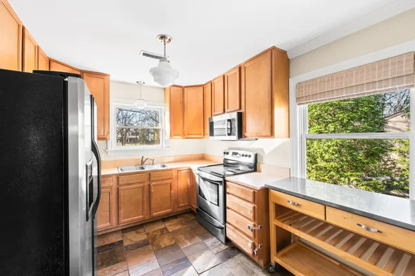 a kitchen with stainless steel appliances granite countertop a refrigerator a sink dishwasher a stove and white countertops with wooden floor