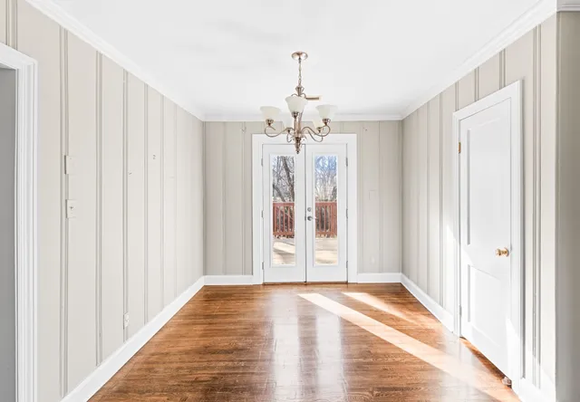 a view of a hallway with wooden floor and chandelier